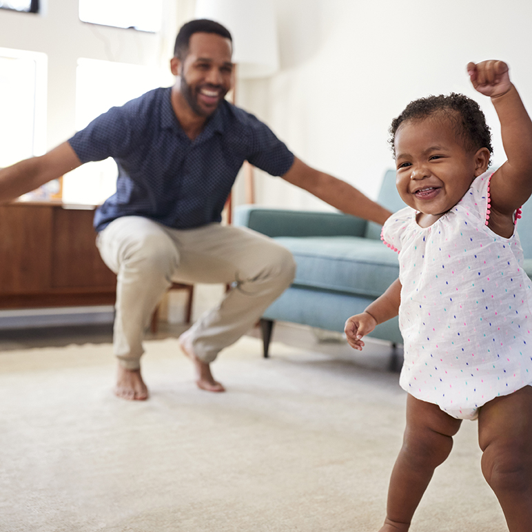 Baby Daughter Dancing With Father In Lounge At Home